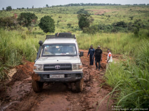 Staff standing around a vehicle stuck in the mud, waiting for assistance